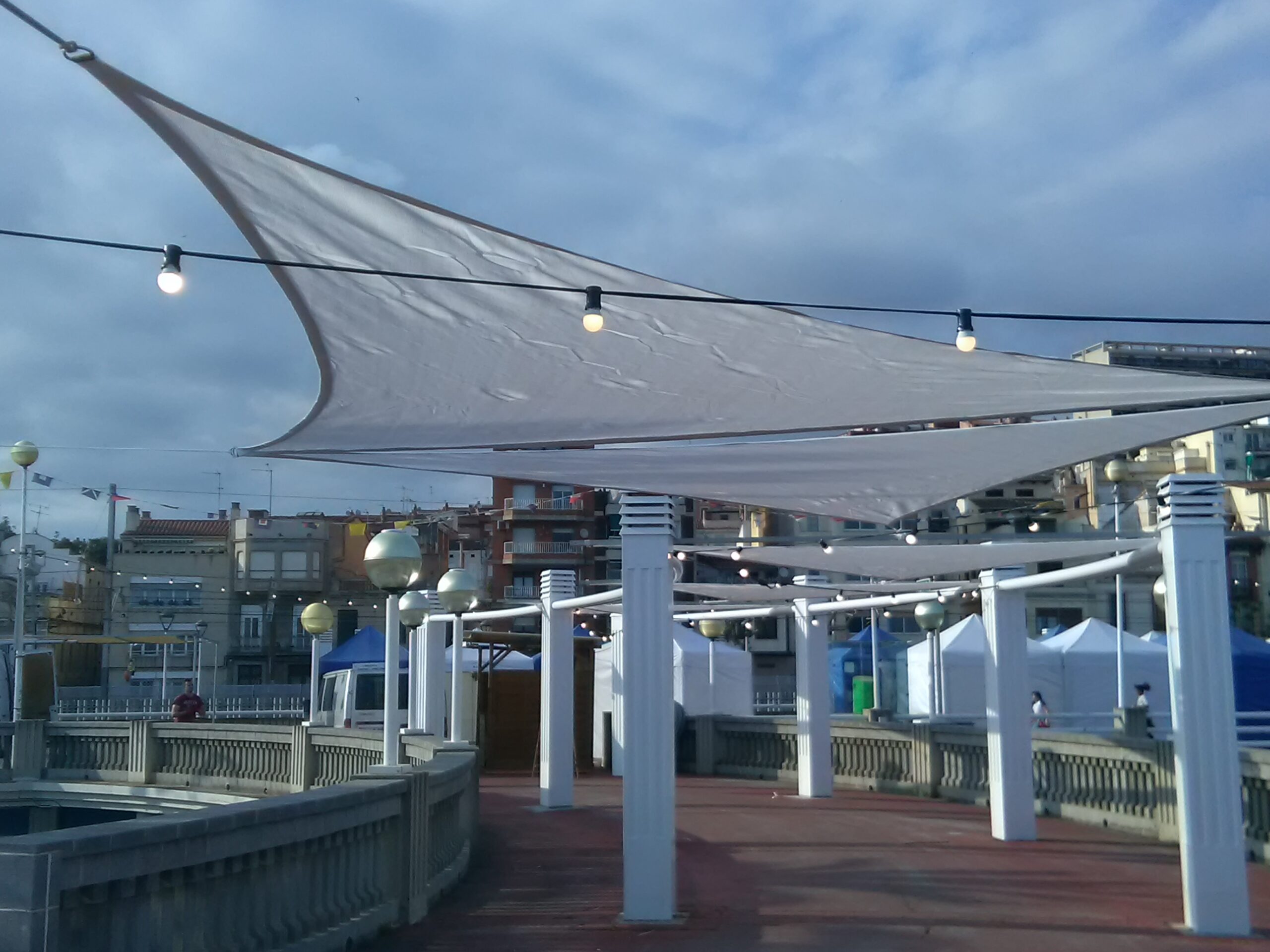 Estructura de sombra tensada sobre mástiles junto al mar